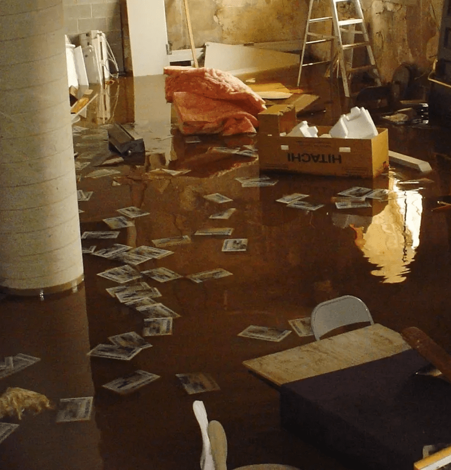 Flooded basement with scattered papers and furniture.
