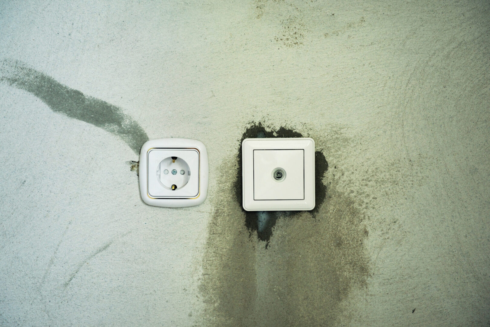 Electrical outlet and switch on stained wall.